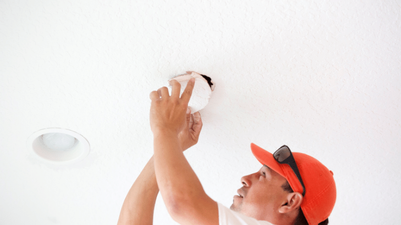 Electrician cutting holes to install lights